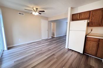A room with a white refrigerator and wooden floors.